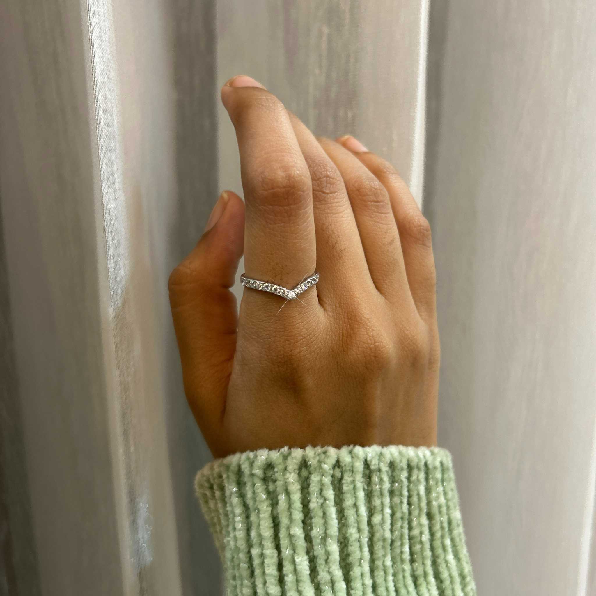 Sparkling silver ring held by a woman's hand on a Stellar silver hypoallergenic V Ring.