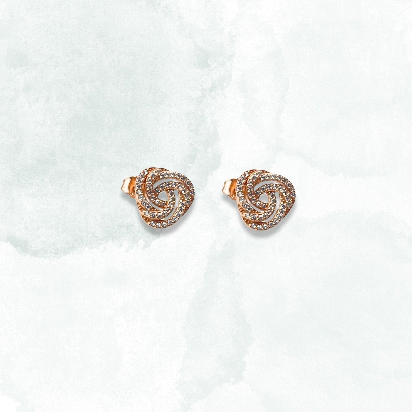 Two diamond stud earrings in rose gold, complemented by a sterling silver ring. Elegant and timeless jewelry pieces